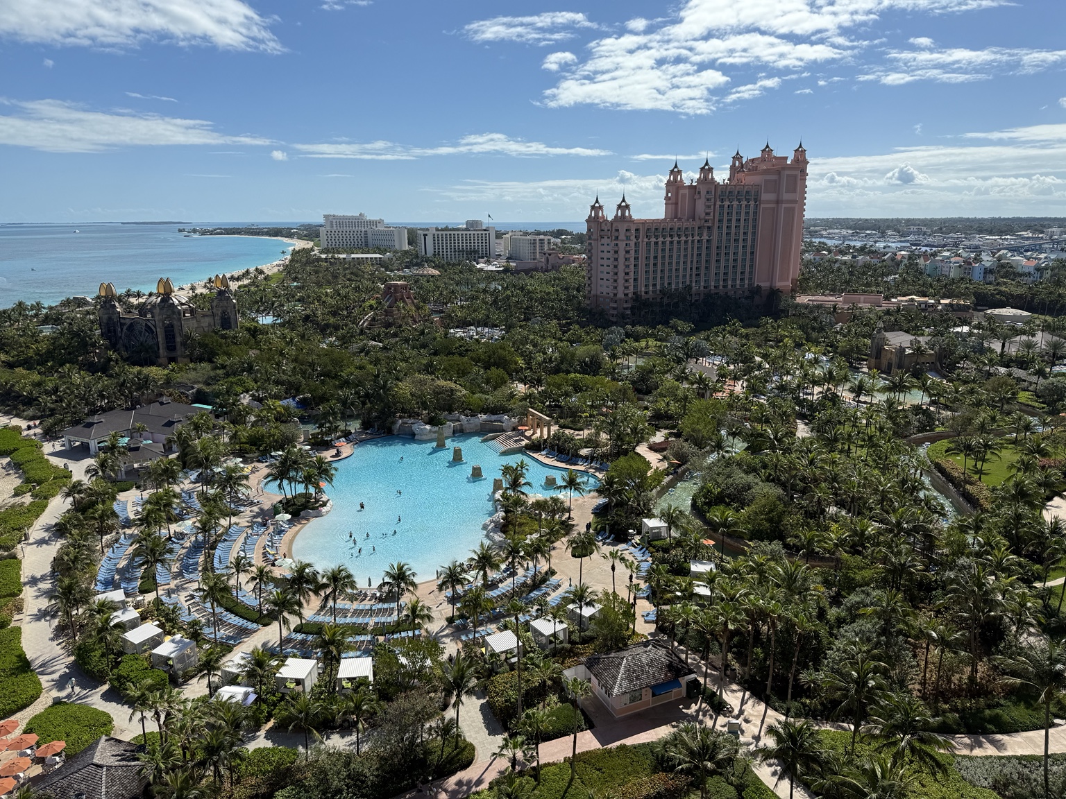 A wide view over the pools, tropical grounds, beach and pink towers of Atlantis Paradise Island
