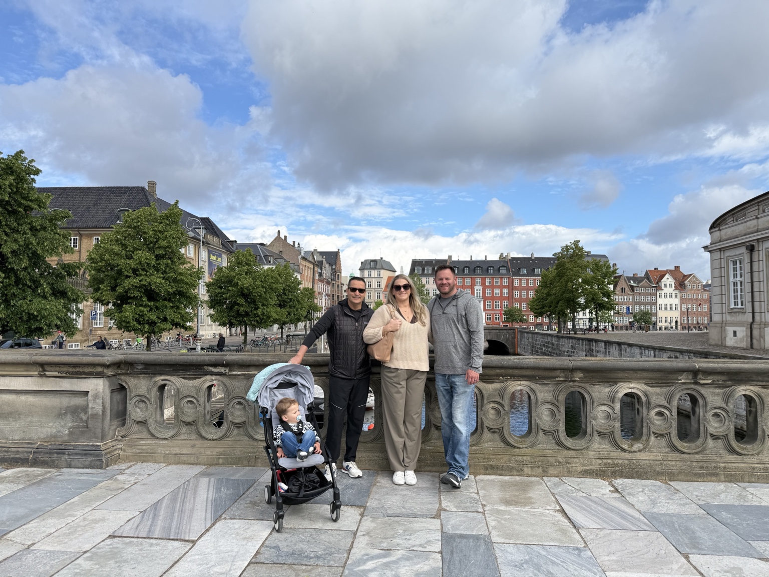 Jeni and family with a toddler in a stroller on a stone bridge in Copenhagen