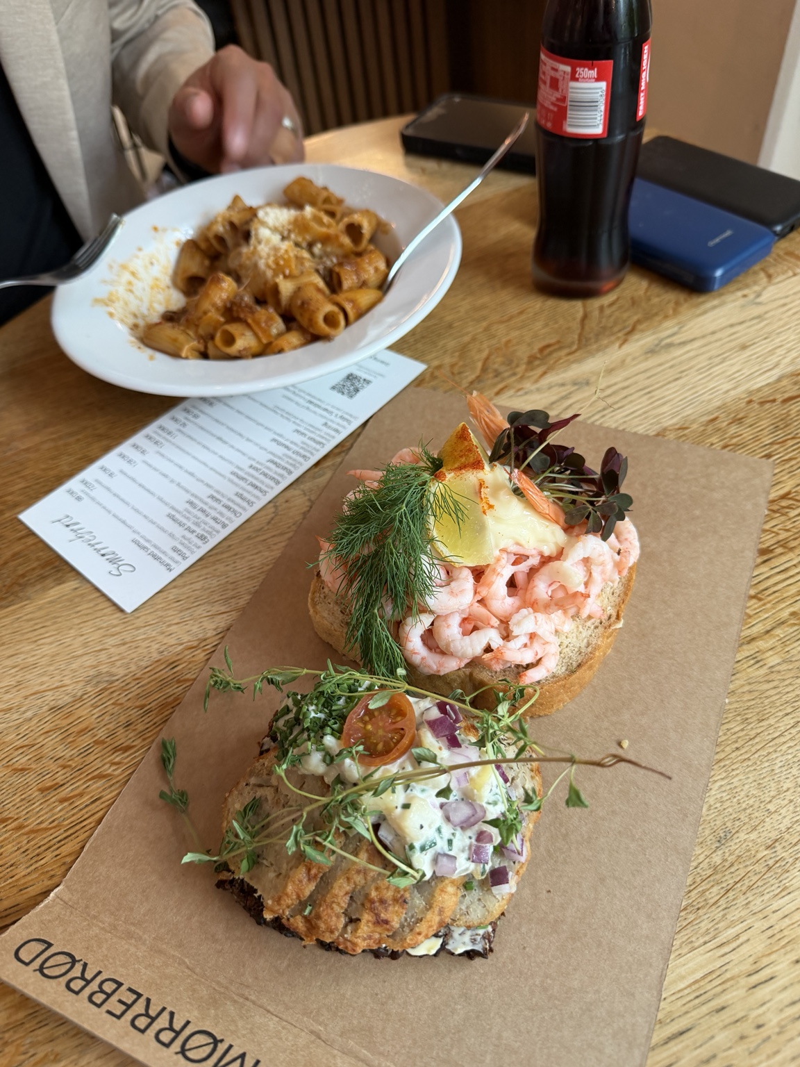 A close-up of two Danish open-faced sandwiches, including one topped with shrimp, lemon and dill