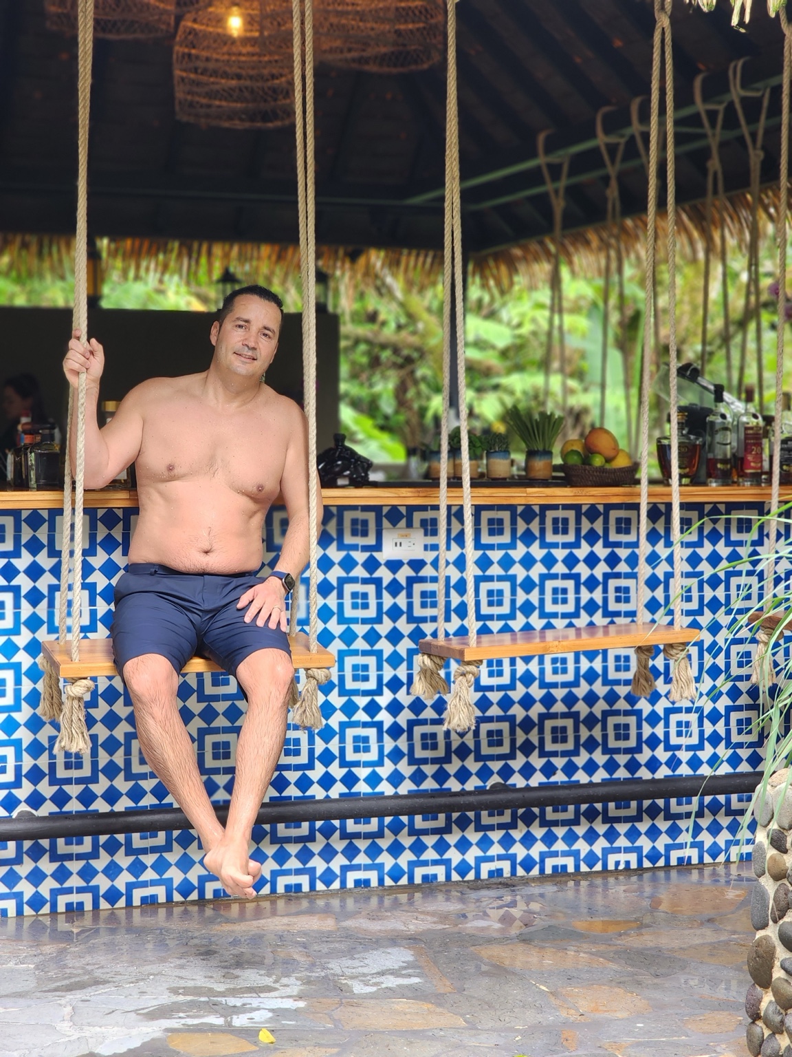 Hassan sitting on a tiled swing beside the pools at Nayara in Arenal