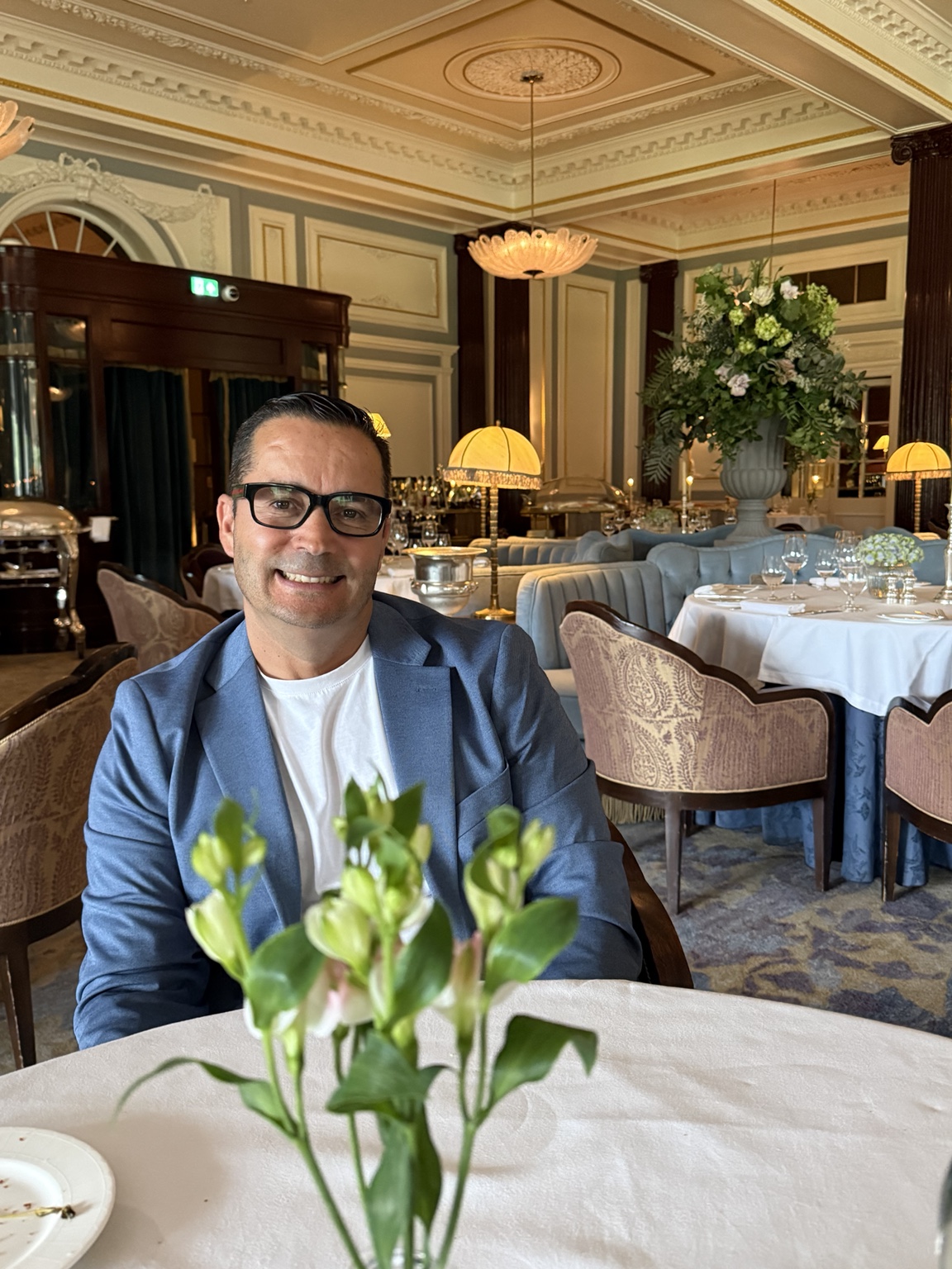 Hassan smiling at a white-clothed table in the elegant dining room at Gleneagles