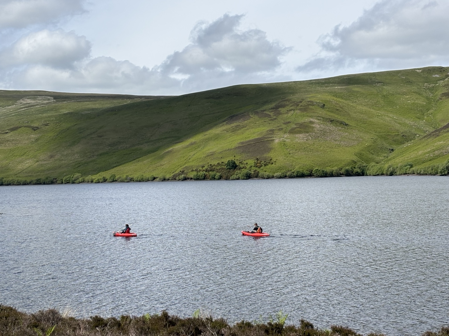 Two kayaks crossing Frandy Water beneath the green Perthshire hills