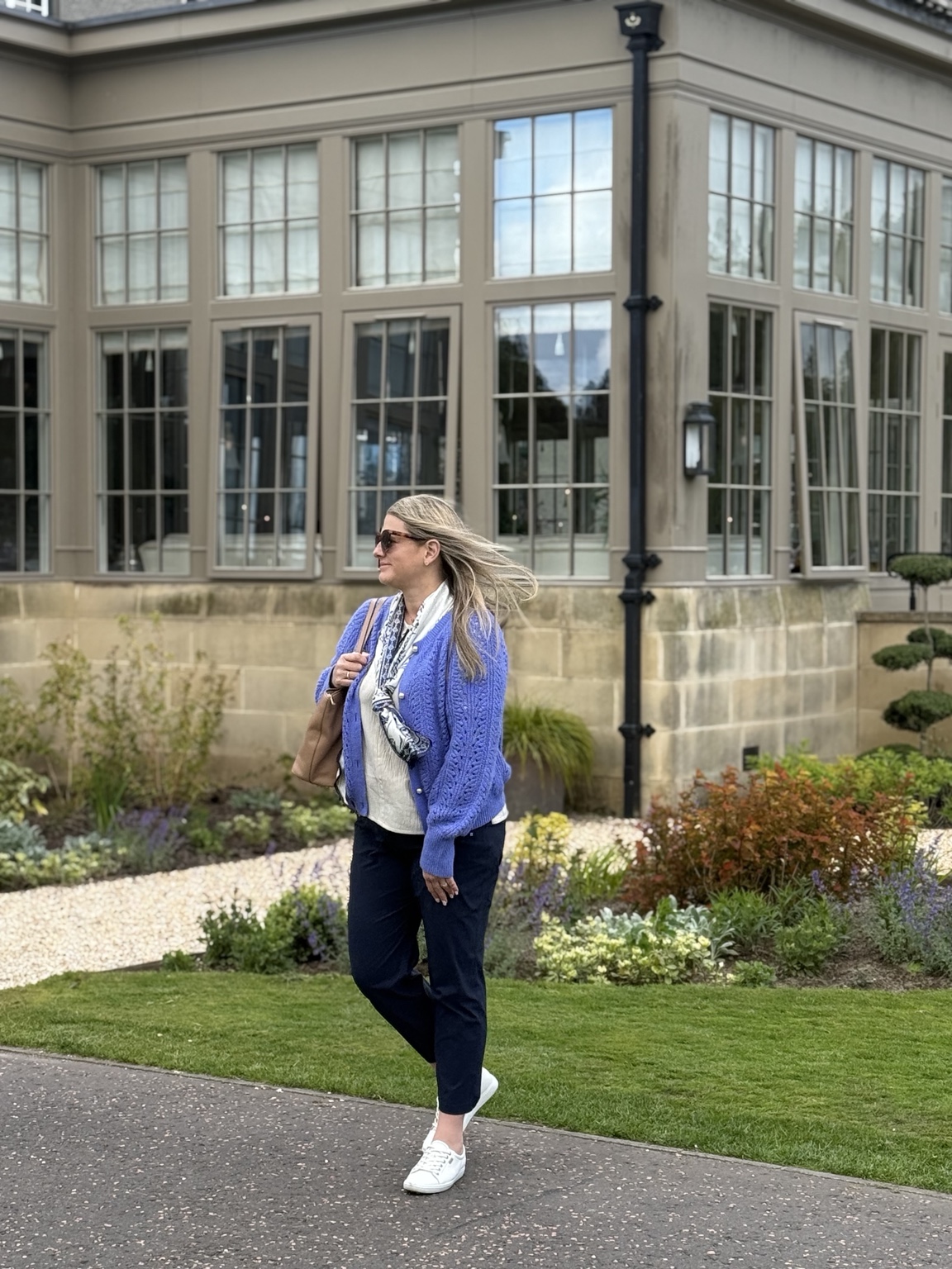 Jeni walking beside the gardens at Gleneagles as the wind catches her hair