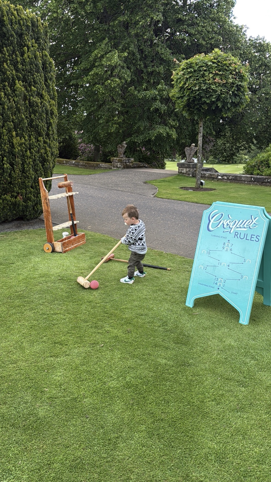 A toddler trying croquet on the lawn at Gleneagles