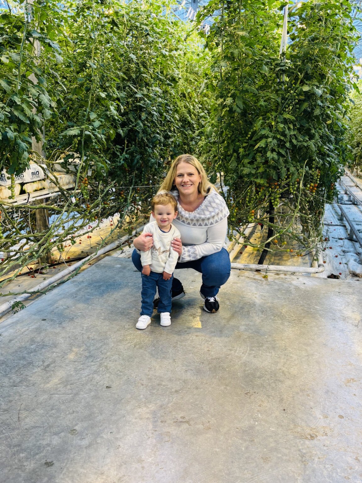 Jeni and her toddler among tall tomato vines inside the Friðheimar greenhouse