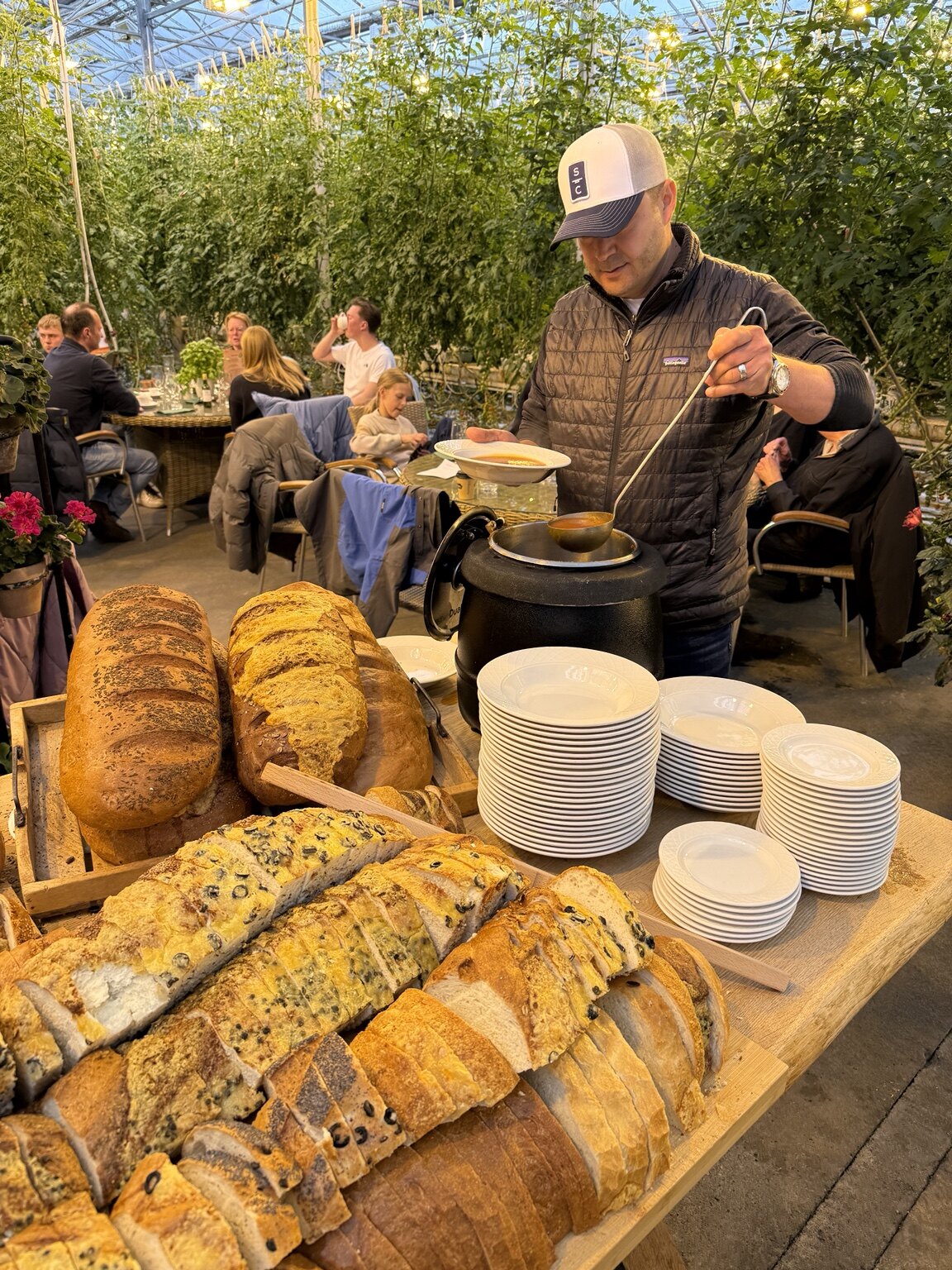 Hassan serving tomato soup beside fresh bread inside the Friðheimar greenhouse