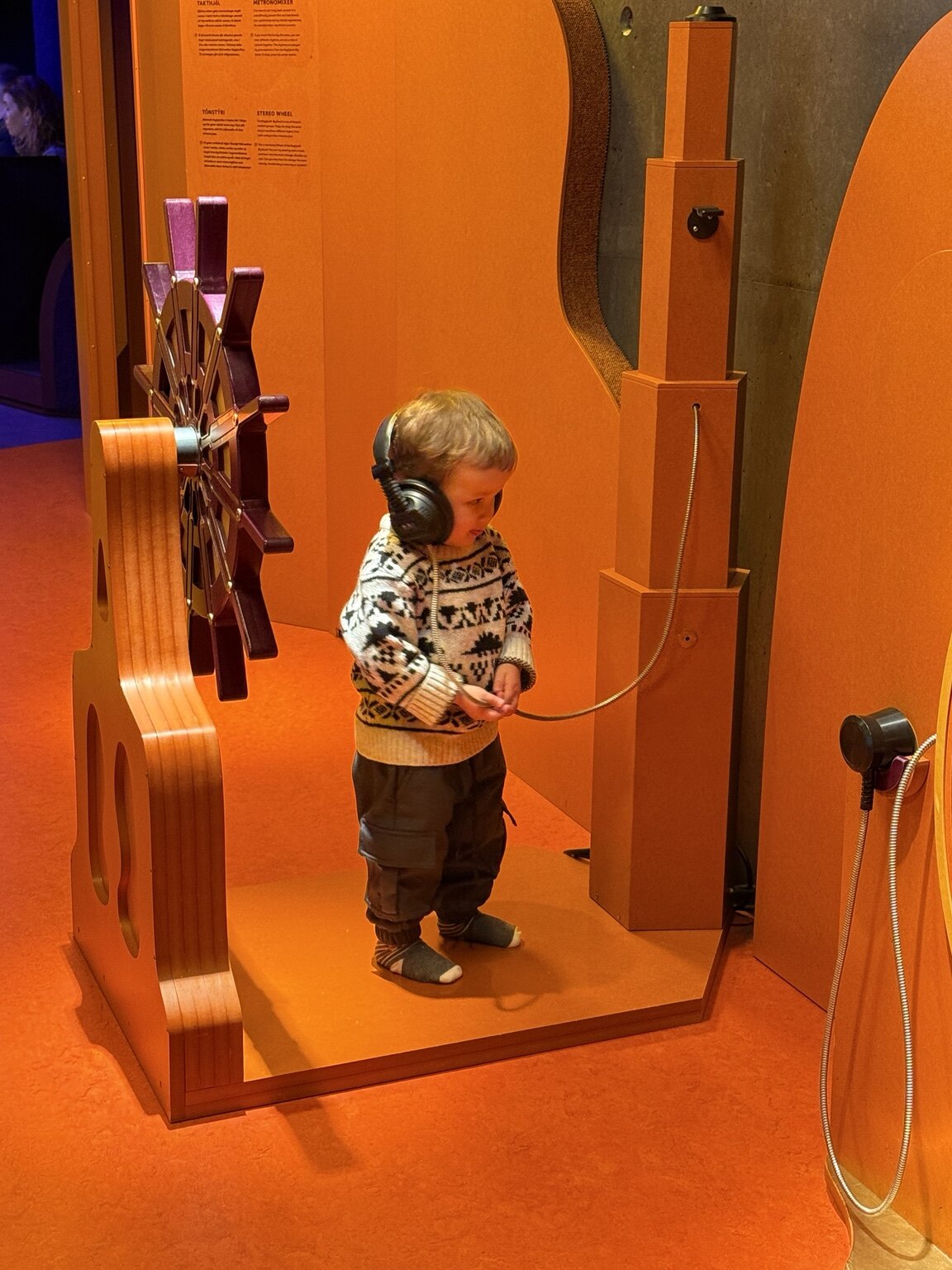 Jeni's toddler wearing headphones and exploring an interactive music installation at Harpa