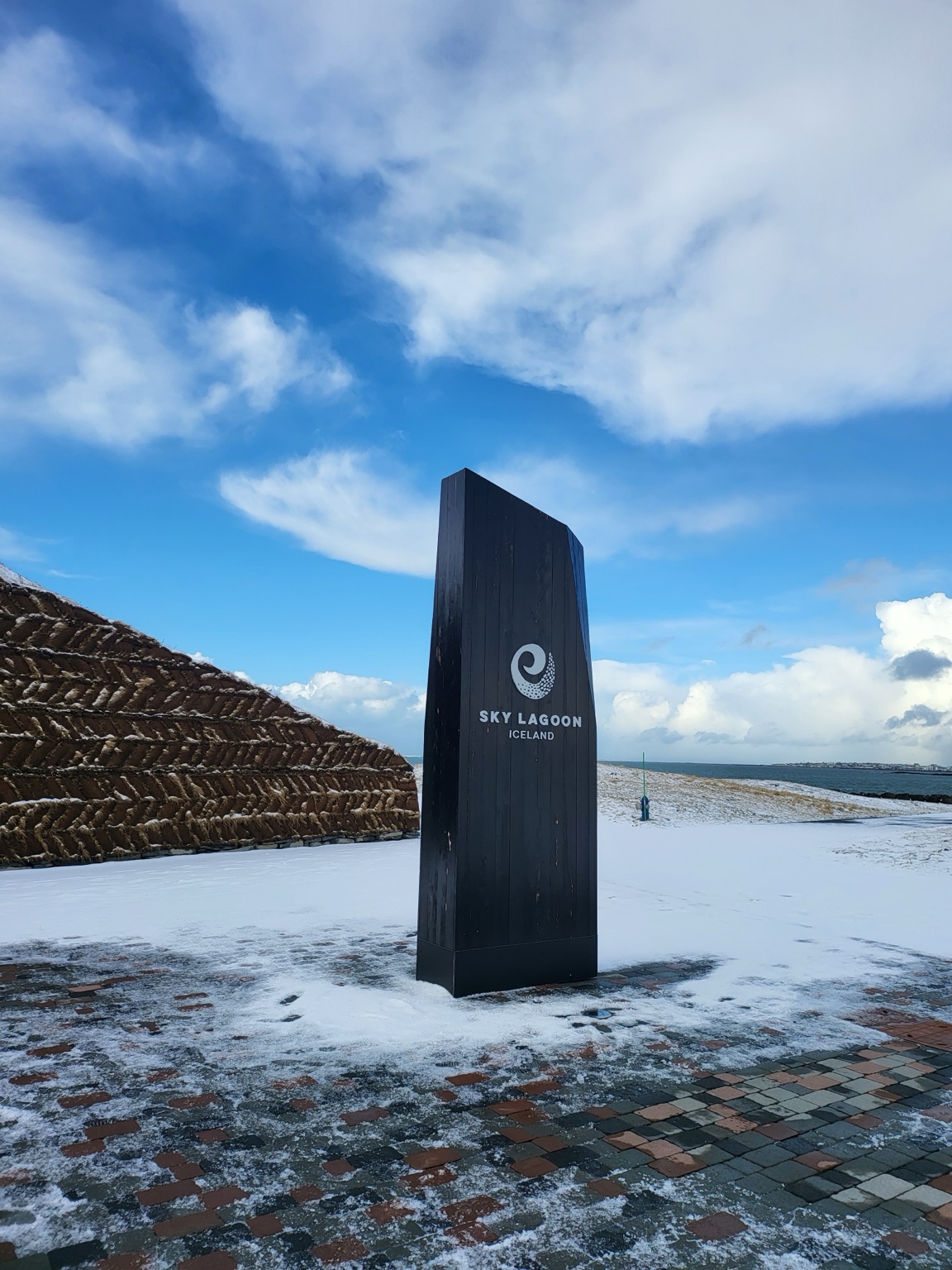 Sky Lagoon entrance marker surrounded by fresh snow beside the Icelandic coast