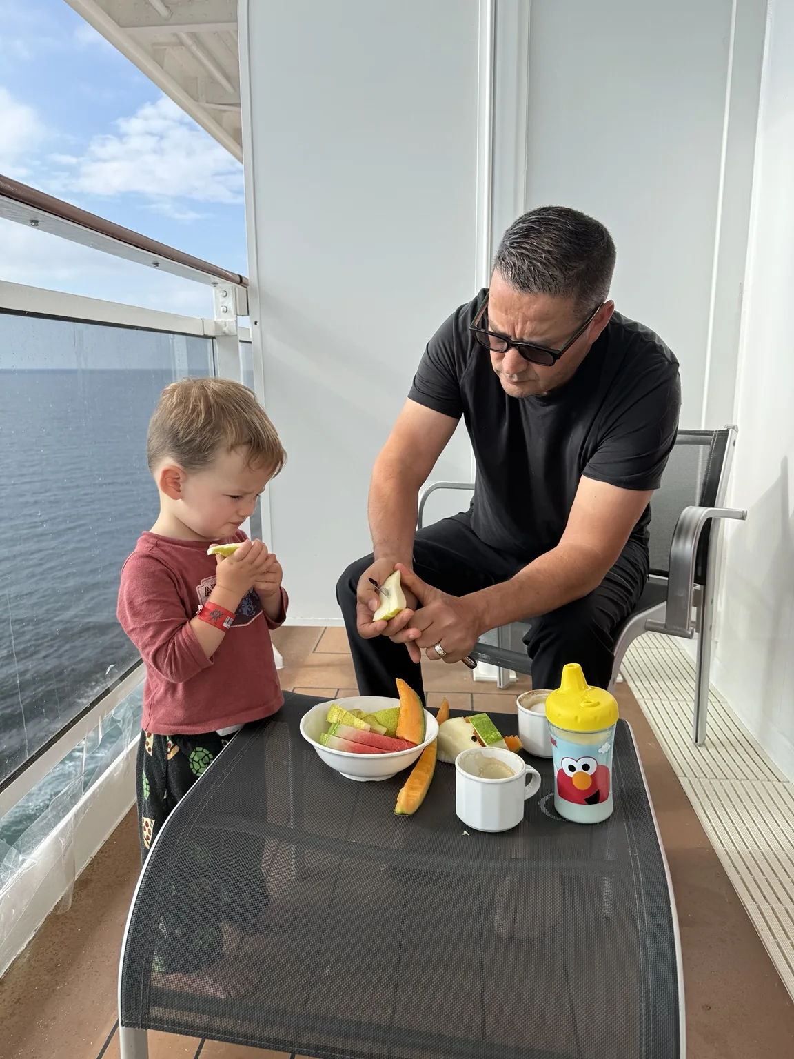 Hassan and our toddler enjoying fruit and breakfast on our cabin balcony