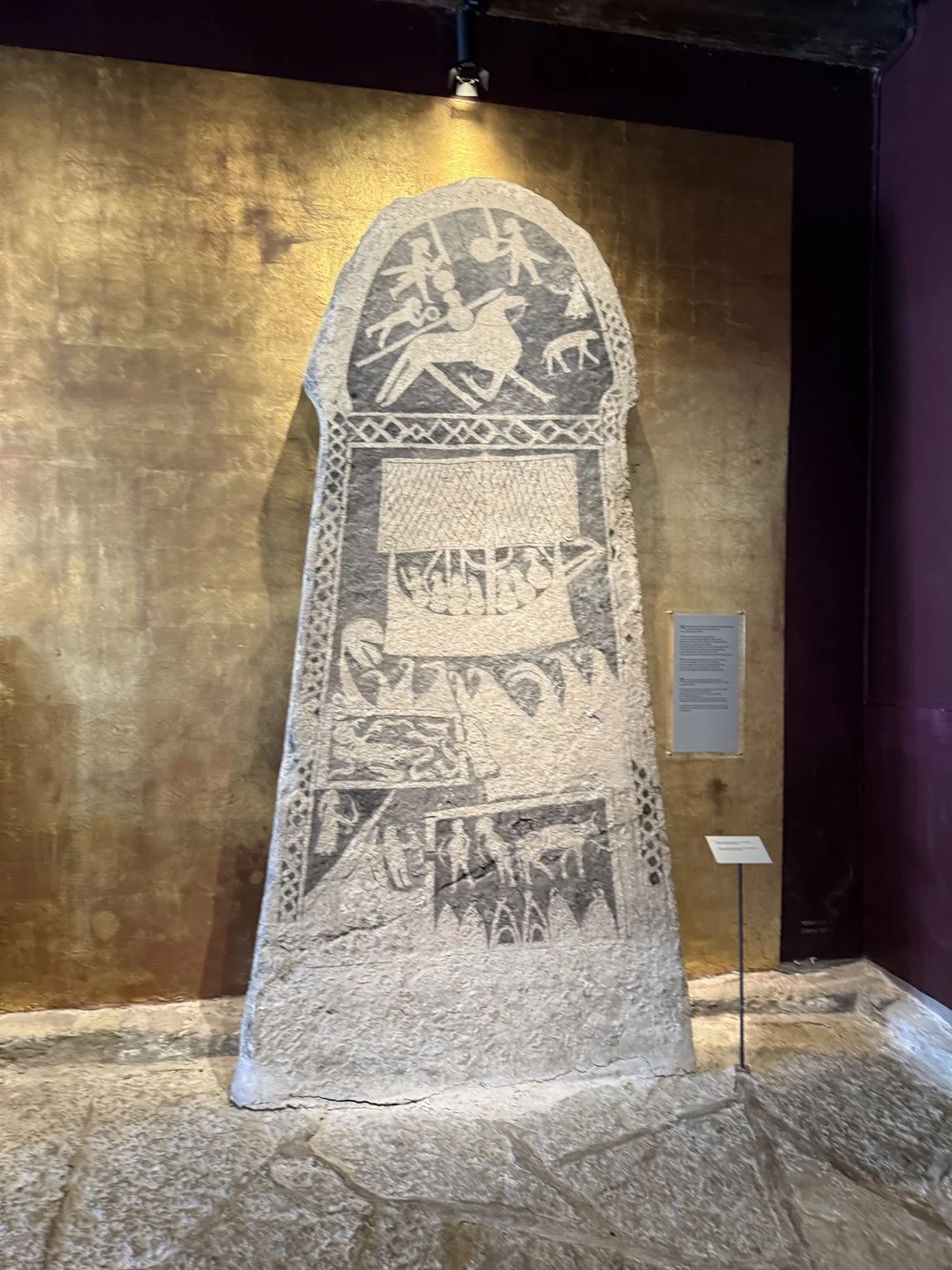 A large Gotlandic picture stone with carved figures and a ship at Gotlands Museum