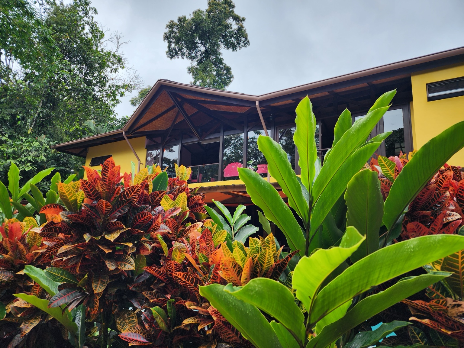 A yellow Nayara Gardens villa rising above colorful tropical foliage in the rainforest