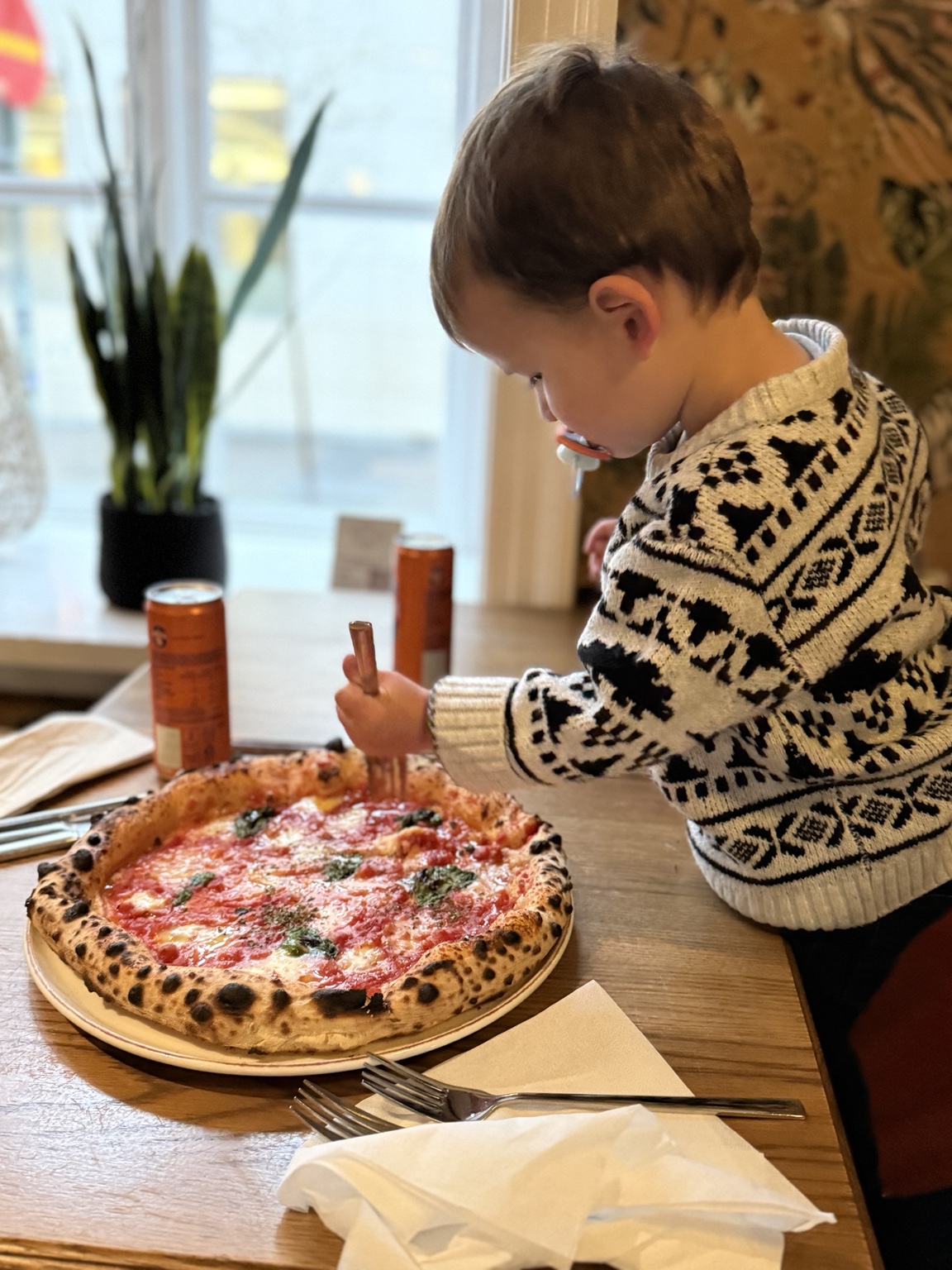 Our toddler beside a freshly baked pizza at Pósthús