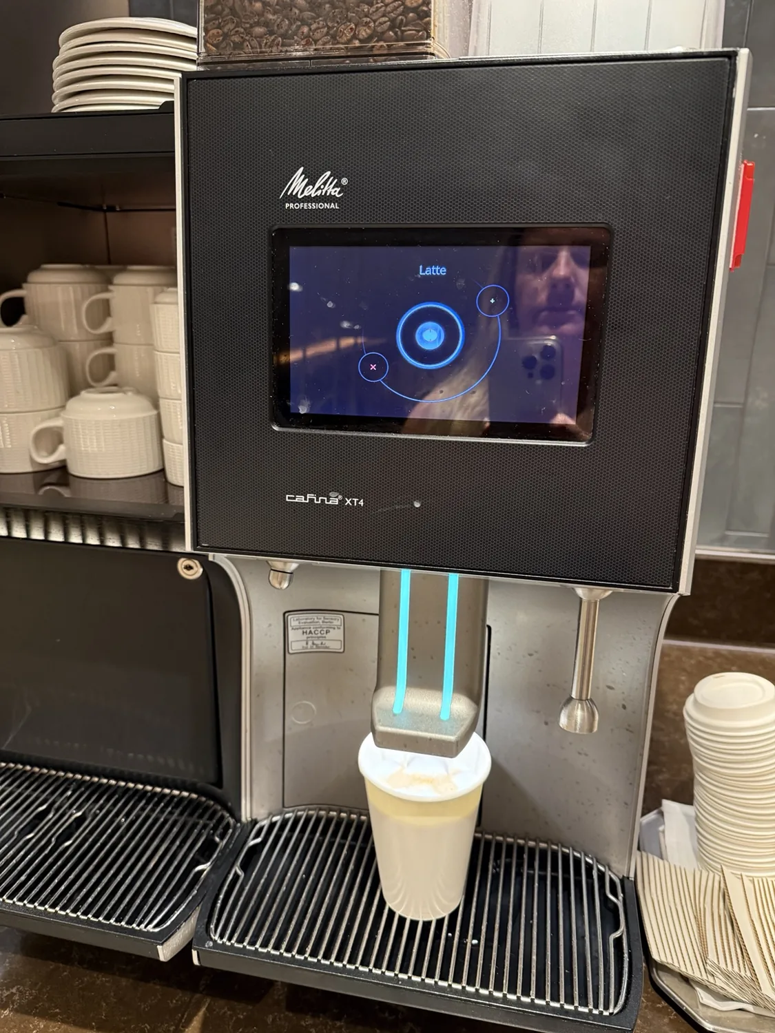 An espresso machine dispensing coffee into a takeaway cup in the suite lounge area