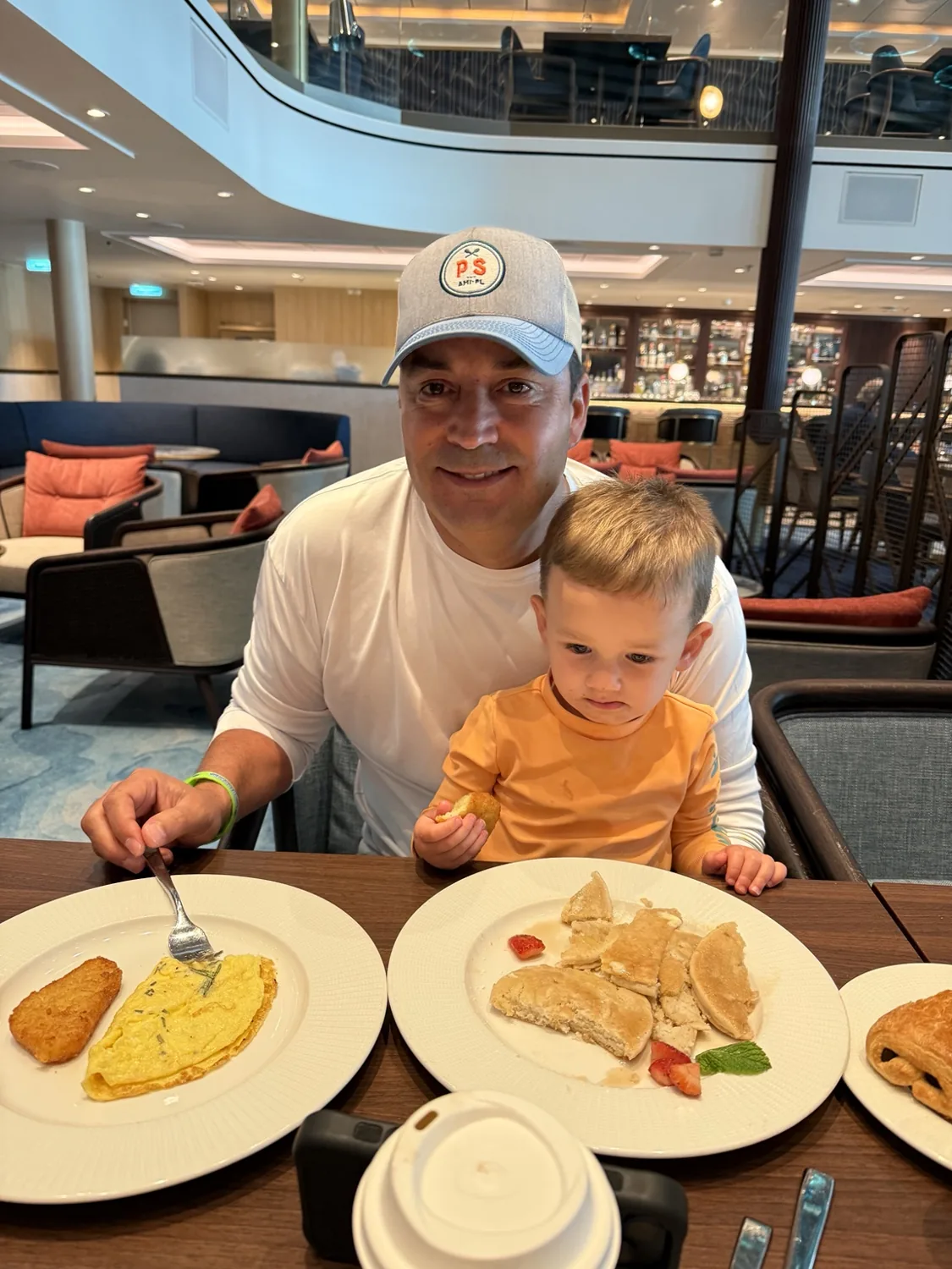 Hassan and our toddler at breakfast in Coastal Kitchen, with pancakes and an omelet on the table