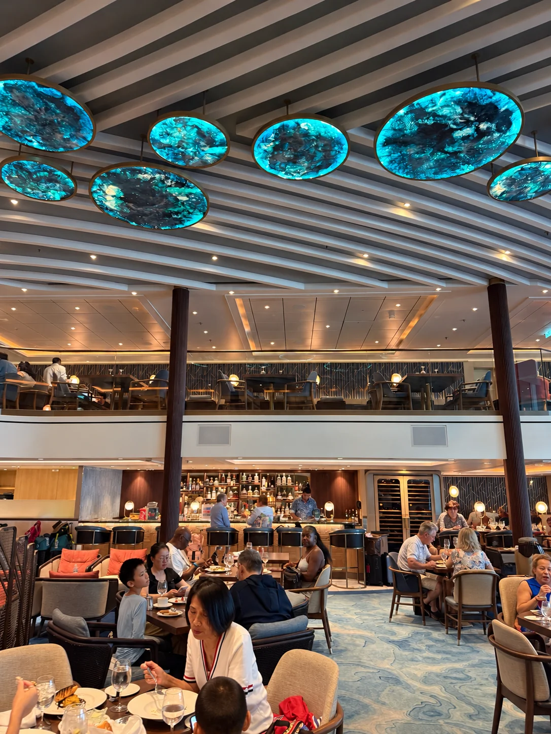 The two-level Coastal Kitchen dining room on Star of the Seas with blue glass ceiling details