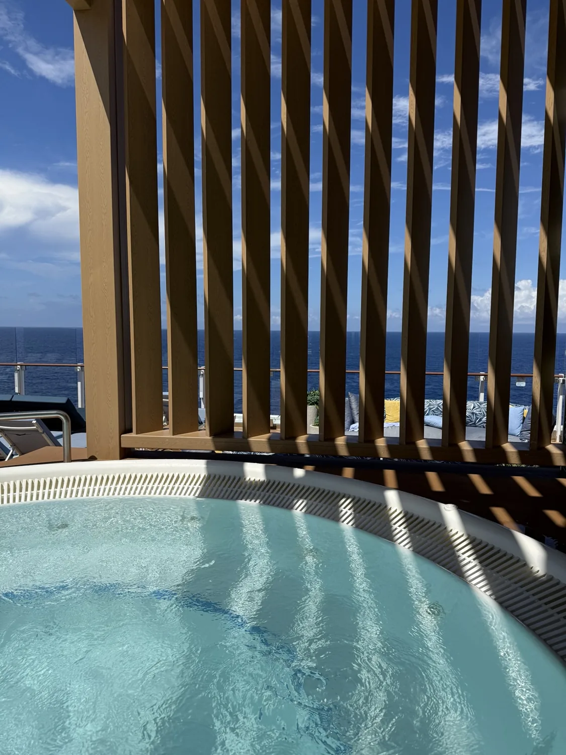 Bubbling water in The Grove’s hot tub, with wooden screening and the sea beyond