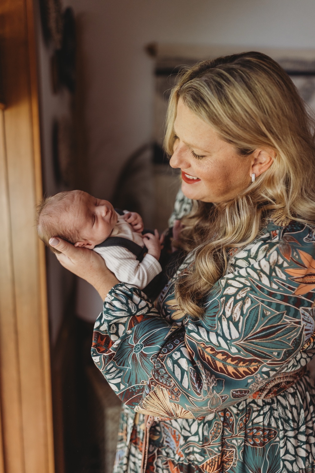 Jeni holding her newborn son near a window